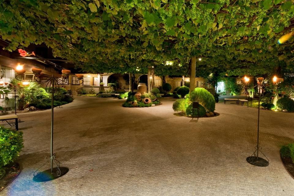 Pátio noturno da Quinta da Mota, entre árvores centenárias e candeeiros de ferro forjado